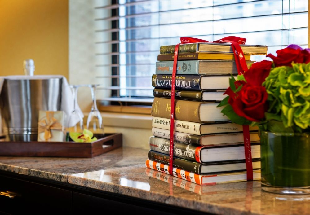 stack of books, floral arrangement, bottle of chilled champagne